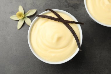 Lezzetli vanilyalı puding, kapsüllü ve çiçekli siyah masa, üst manzara.