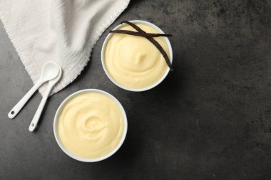 Siyah masada kapsüllü ve kaşıklı lezzetli vanilyalı puding. Metin için boşluk