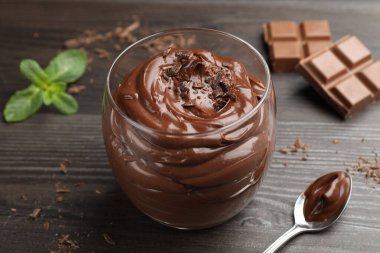 Bardakta çikolatalı puding, ahşap masada kaşık, yakın plan.