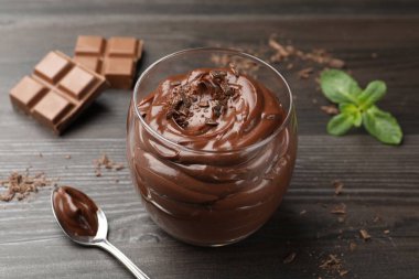 Bardakta çikolatalı puding, ahşap masada kaşık, yakın plan.