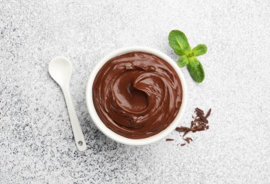 Lezzetli çikolatalı puding kasede, talaş, nane ve kaşık açık gri desenli masa, düz uzanmış