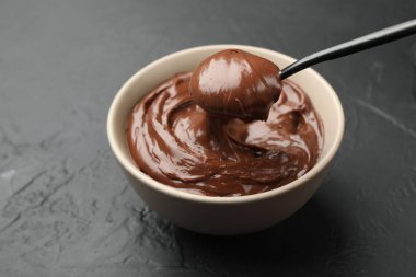 Siyah masadaki kaşıkla kaseden lezzetli çikolatalı pudingi alıyorum. Yakın plan.