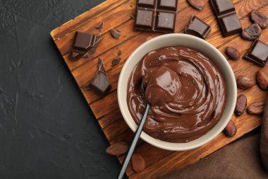 Kâsede lezzetli puding, çikolata ve kakao çekirdekleri siyah masada, düz yerde.