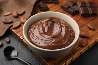 Kasede lezzetli puding, çikolata parçaları ve siyah masada kakao çekirdeği, yakın plan.