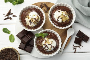 Krem şantili lezzetli puding, beyaz ahşap masa üzerinde çikolata ve kaşık parçaları, düz yatıyordu