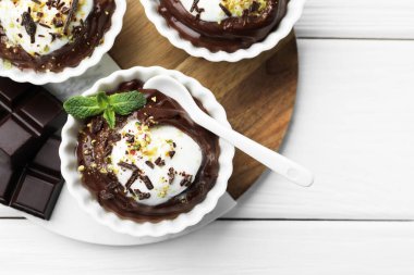 Krem şantili lezzetli puding, beyaz ahşap masa üzerinde çikolata ve kaşık, düz yatak. Metin için boşluk