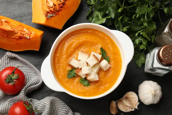 Lezzetli balkabağı kremalı çorba, kızarmış ekmek ve diğer ürünler arasında kasede maydanoz.