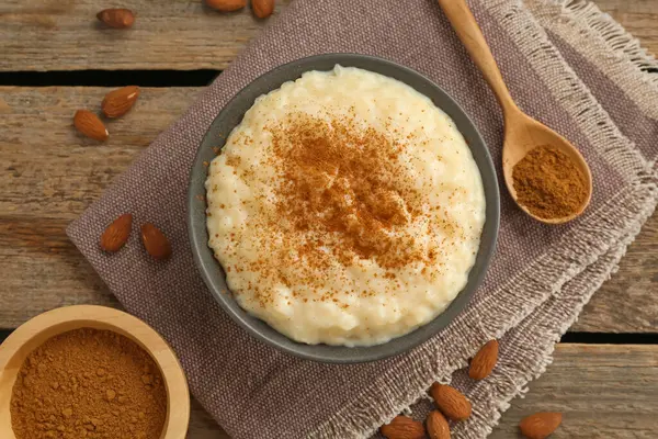 Tarçınlı lezzetli sütlaç ve ahşap masada badem.
