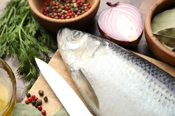Tuzlu ringa balığı, baharat ve bıçak masanın üstünde.