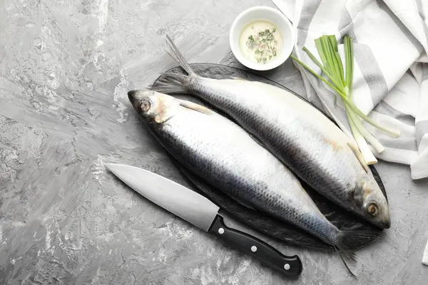 Tuzlu ringa balıkları, baharatlar ve bıçak gri masada, düz yerde. Metin için boşluk