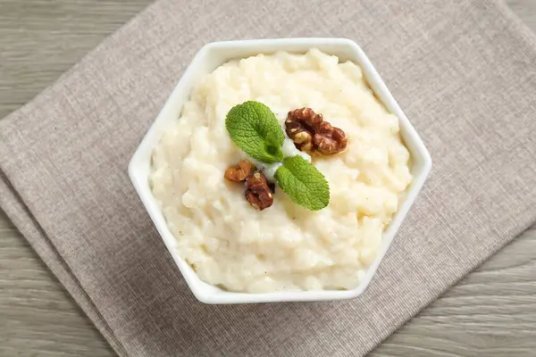 Cevizli lezzetli sütlaç ve ahşap masada nane şekeri.