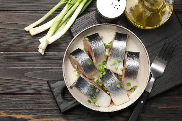 Lezzetli ringa balıkları. Yeşil soğanlı. Siyah ahşap masada servis ediliyor.