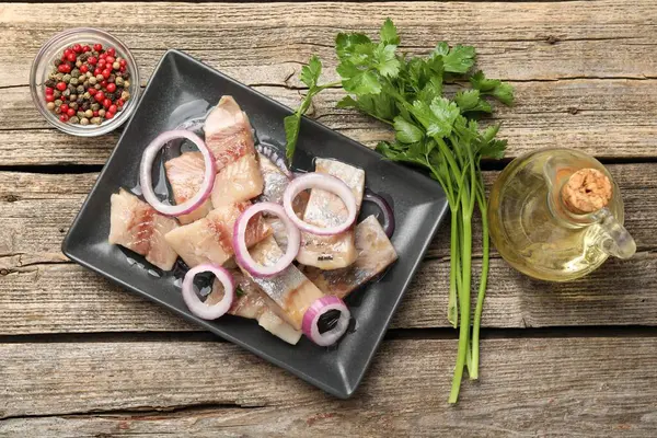 Soğanlı, biberli, ahşap masada yağlı ve maydanozlu ringa balıkları.