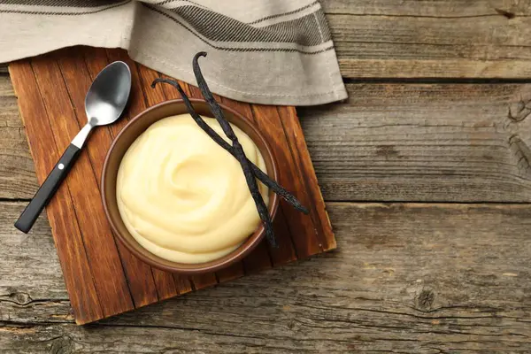 Lezzetli vanilyalı puding ve kapsüller ahşap masada, düz yerde. Metin için boşluk
