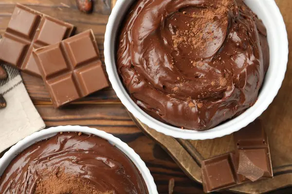 Tabaklardaki lezzetli pudingler, çikolata parçaları ve kakao çekirdekleri ahşap masada, düz yatıyordu.