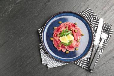 Taze et carpaccio roka, limon ve kapari, koyu dokulu masa, üst manzara. Metin için boşluk