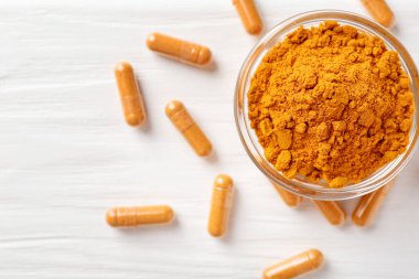 Zerdeçal kapsülleri ve toz beyaz ahşap masa üzerinde, düz yerde. Metin için boşluk