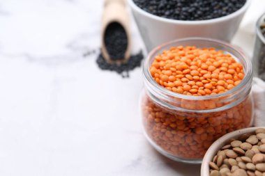 Beyaz masada farklı türde mercimek, yakın plan. Metin için boşluk