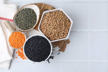 Beyaz fayanslı masa üzerinde farklı mercimek türleri, üst görünüm. Metin için boşluk