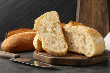 Farklı türde taze ekmek ve bıçak koyu dokulu masa, yakın plan.