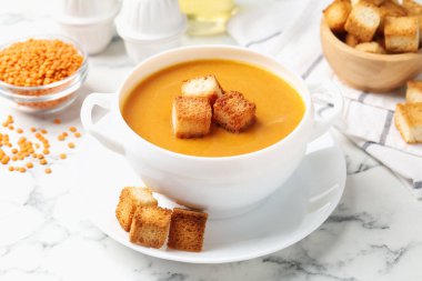 Lezzetli mercimek kremalı çorba ve beyaz mermer masada kızarmış ekmek.