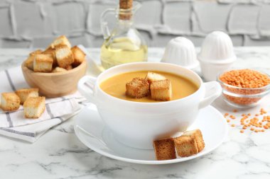 Lezzetli mercimek kremalı çorba ve beyaz mermer masada kızarmış ekmek.