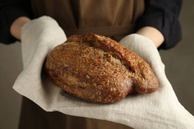 Gri arka planda taze ekmek somunu olan kadın, yakın plan.