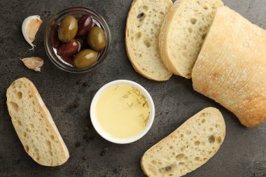 Yağ, zeytin ve baharatlı dilimlenmiş ekmek siyah masada, düz yerde.