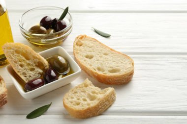 Beyaz ahşap masada yağlı ve zeytinli dilimler, yakın plan.