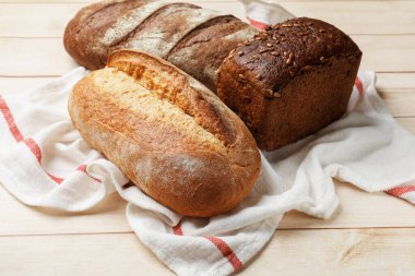 Tahta masadaki farklı taze ekmek türleri, yakın çekim.