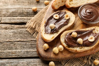 Çikolata sürülmüş ekmek dilimleri ve ahşap masada fındıklar, düz yatak. Metin için boşluk