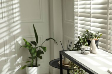 Pencerenin yanında farklı dekorları olan konsol masası, yakın çekim. İç tasarım