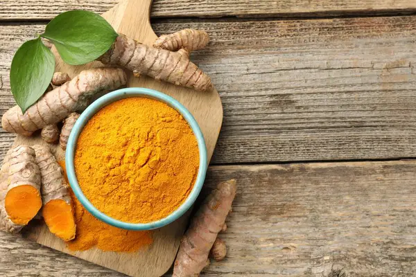 Kasede zerdeçal tozu, kökler ve yapraklar ahşap masada, düz yerde. Metin için boşluk