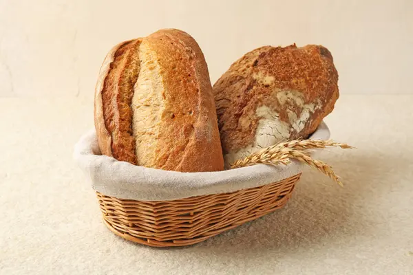 Hasır sepetin içinde farklı türde taze ekmek ve çiviler açık desenli masa üzerinde, yakın plan.