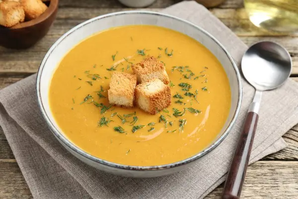 Ahşap masada sunulan lezzetli mercimek kremalı çorba, yakın plan.