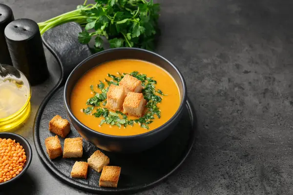 Gri masadaki kızarmış ekmeklerle servis edilen lezzetli mercimek kremalı çorba, yakın plan. Metin için boşluk