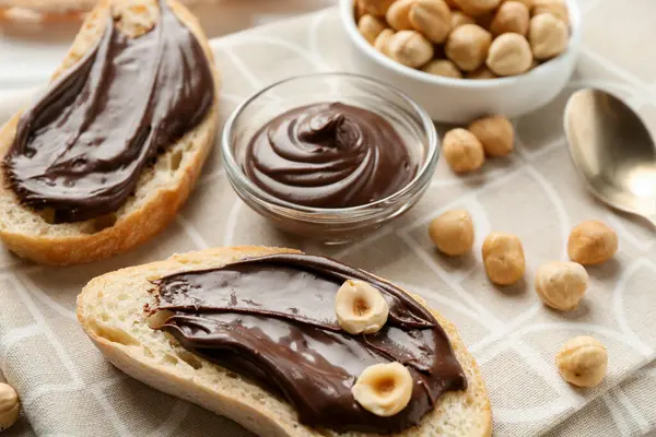 Çikolatalı ekmek dilimleri ve masada fındıklar, yakın plan.