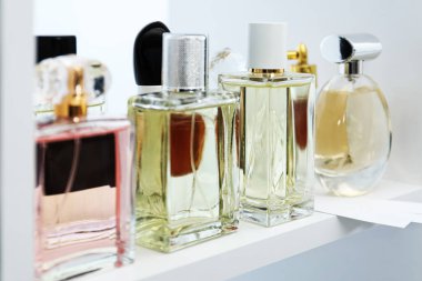 Dükkandaki raflarda farklı parfüm şişeleri ve parfümler var.