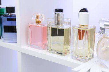 Dükkandaki raflarda farklı parfüm şişeleri ve parfümler var.