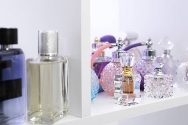 Dükkandaki raflarda farklı lüks parfüm şişeleri var.