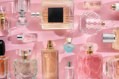 Pembe arka planda çeşitli parfüm şişeleri, düzlük