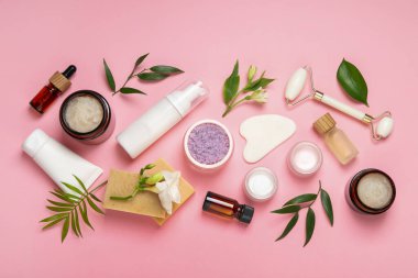 Pembe arka planda farklı vücut bakım ürünleriyle düz konum