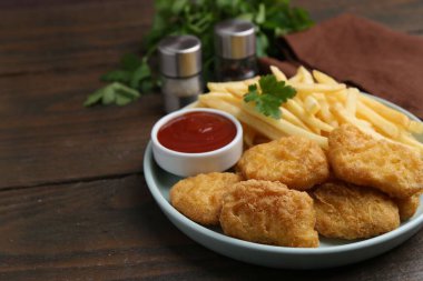 Lezzetli tavuk nugget ve ahşap masada soslu patates kızartması, yakın plan.