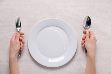 Sofrada çatal bıçaklı ve boş tabağı olan bir kadın.