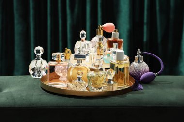 Deniz mavisi perdelerin yanındaki yeşil puf üzerinde farklı lüks parfümler.