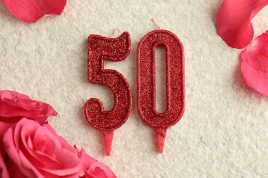 50. yaş günü. Işık desenli arkaplanda mumlar ve güller var.