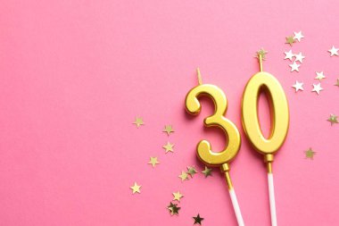 30th birthday. Number shaped candles and confetti on pink background, flat lay. Space for text