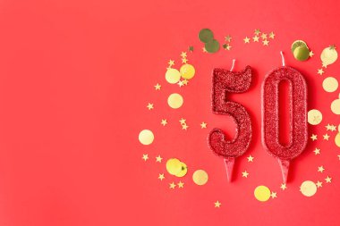 50. yaş günü. Kırmızı arkaplandaki mumlar ve konfetiler düzdü. Metin için boşluk