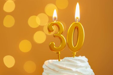 30. yaş günü. Kek üzerindeki mumların yanma sayısı altın arka planda bulanık ışıklar, yakın çekim ve metin için boşluk. Bokeh etkisi