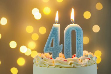 40. yaş günü. Pastanın üzerinde yanan mumlar arka planda bulanıklık yaratıyor. Işıklar, yakın plan. Bokeh etkisi